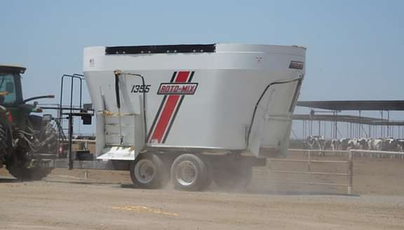 1355 trailer with a tractor hooked up driving on a dairy.